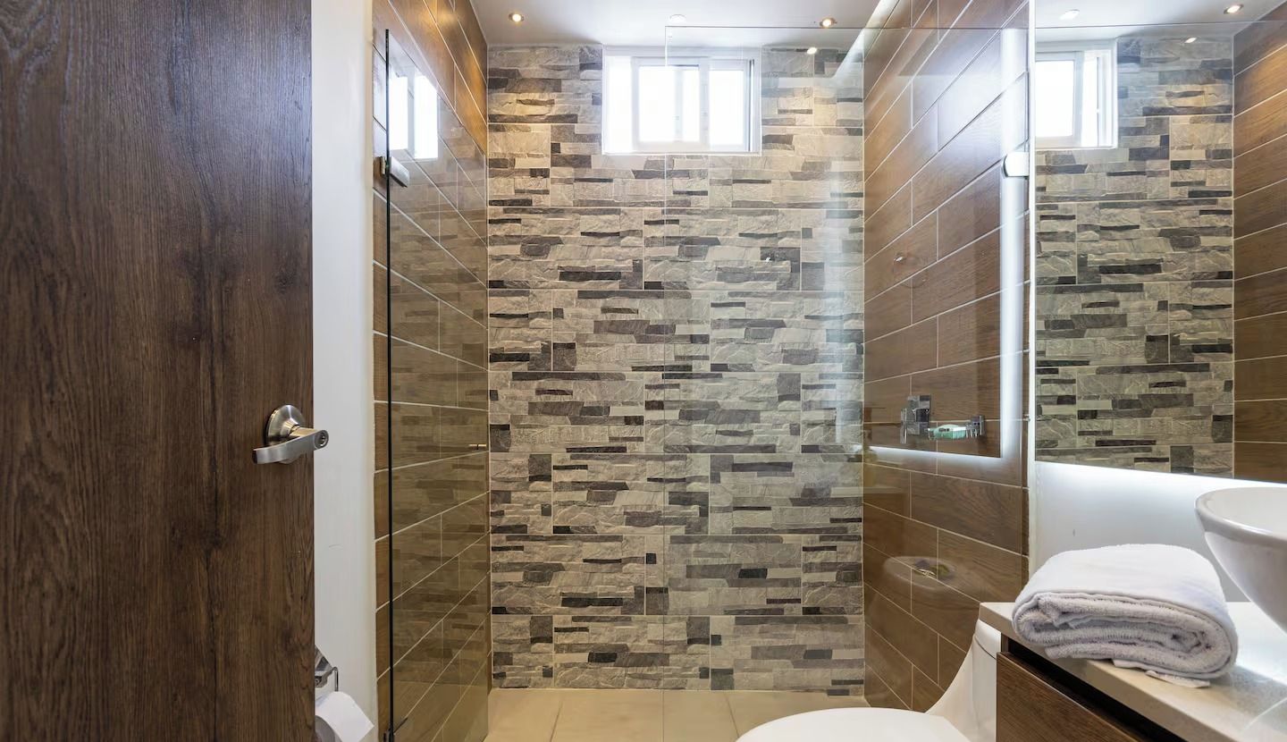 Un baño con pared de piedra, inodoro y lavamanos.