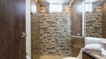 Un baño con pared de piedra, inodoro y lavamanos.