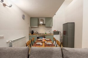 A compact kitchen with a dining table set for four, a refrigerator, and a microwave.