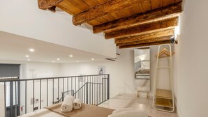 A bedroom with a wooden ceiling, a bed with towels, a ladder, and a bathroom with a mirror and towel rack. - Loft 'Kiccifù Home Palermo' with Wi-Fi and Air Conditioning (Palermo)