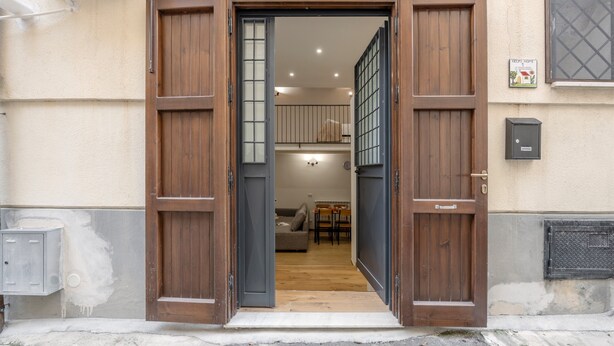A wooden door with glass panels leading into a room with a sofa and a dining table. - Loft 'Kiccifù Home Palermo' with Wi-Fi and Air Conditioning (Palermo)