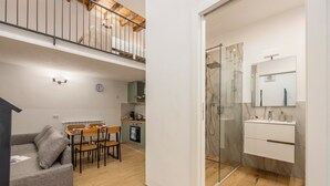A modern apartment with a dining area, kitchenette, and a glass shower enclosure. - Loft 'Kiccifù Home Palermo' with Wi-Fi and Air Conditioning (Palermo)