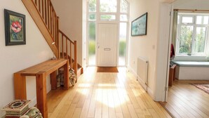 Un hall d’entrée spacieux, doté d’un plancher en bois, d’un banc en bois, d’un escalier et d’une porte donnant sur l’extérieur.