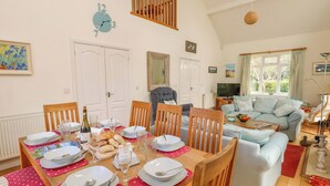 Un coin repas avec une table en bois mise pour le repas, un canapé et un téléviseur dans le salon.