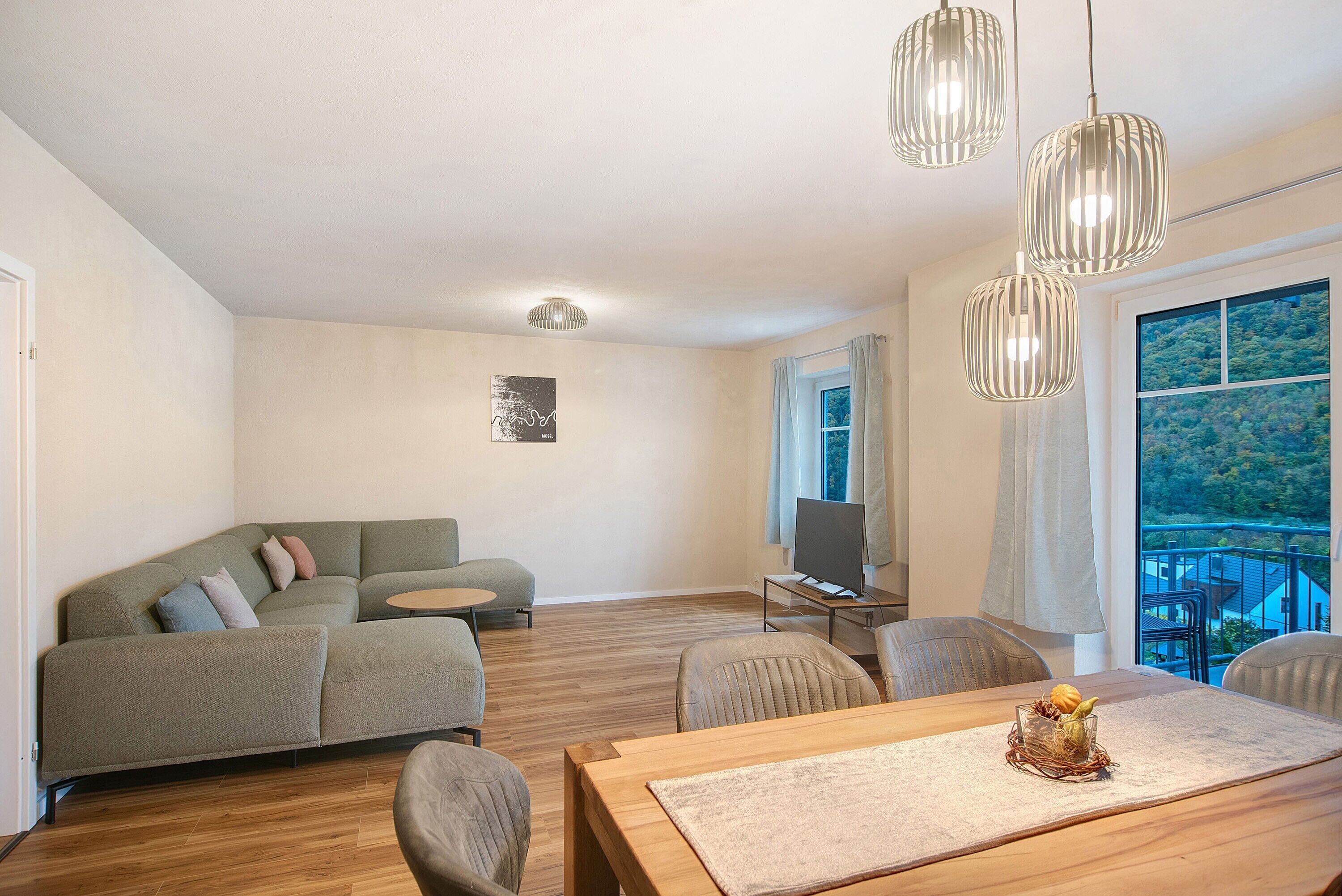 Un salon moderne avec un canapé, une table à manger et des luminaires suspendus.