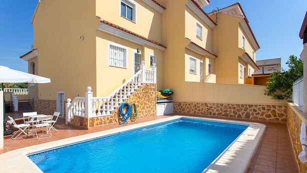 A swimming pool with a stone wall and a white railing.