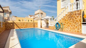 A swimming pool with stone walls and a clear blue sky.