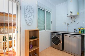 A compact kitchen with a washing machine, a drying machine, and a water heater.