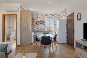 A compact kitchen with a dining area, a washing machine, and a TV.