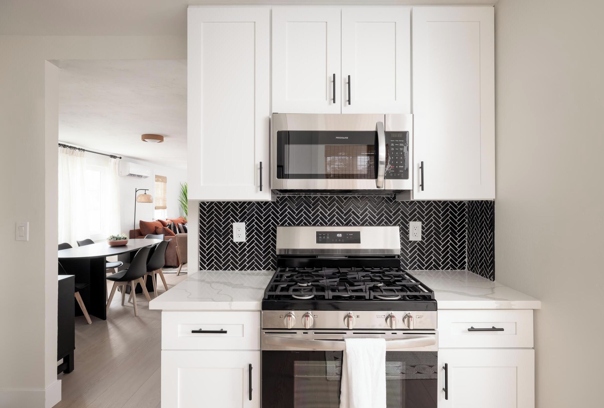 A modern kitchen with white cabinetry, a stainless steel stove, and a microwave.