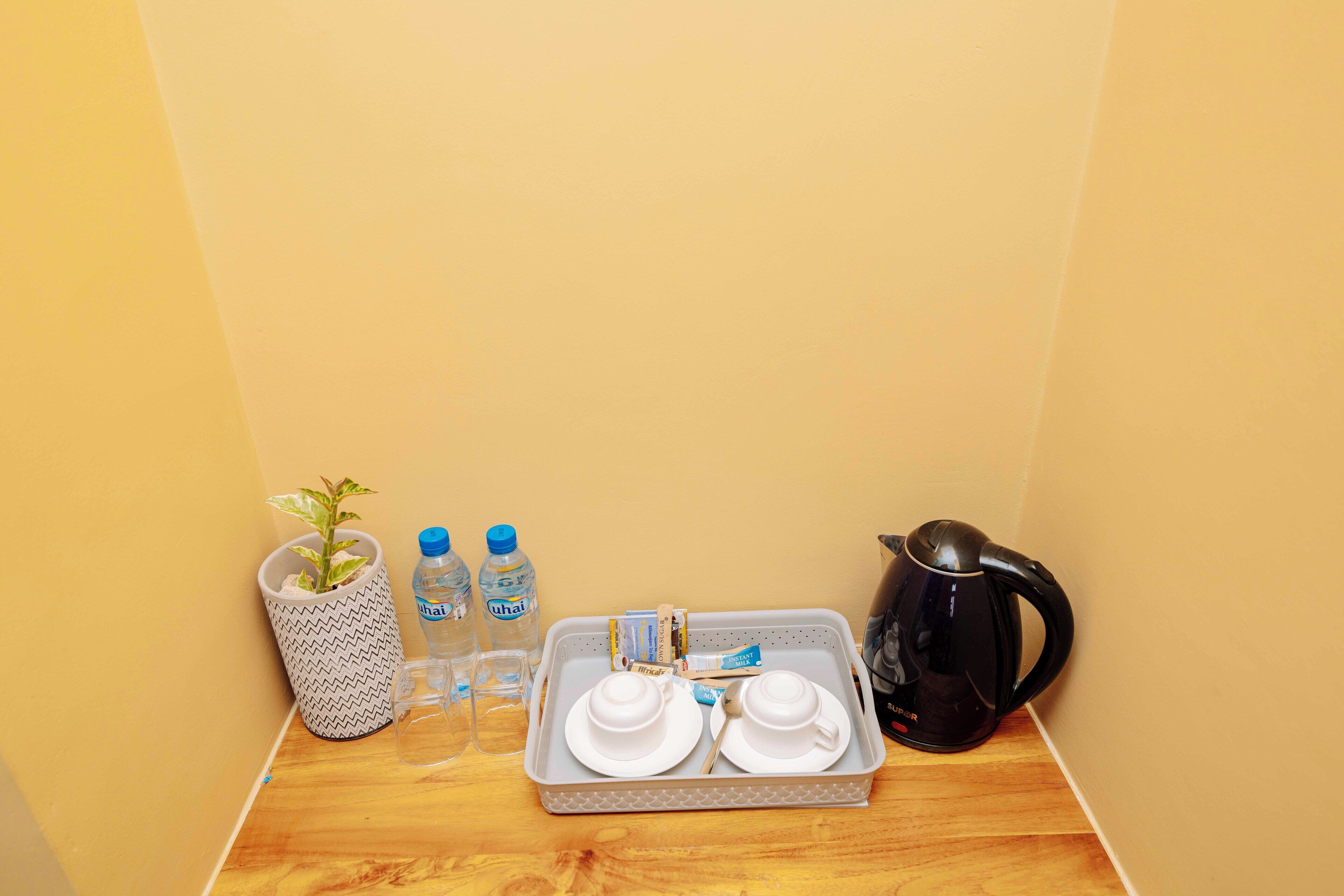 A tray with white dishes and a black coffee pot on a wooden surface.
