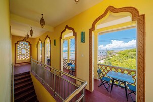 Una escalera conduce a un balcón con vistas a zonas verdes y un cielo despejado.
