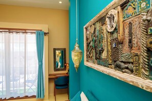 Een kamer met teal muren, een houten stoel, een bureau en een groot decoratief wandobject.