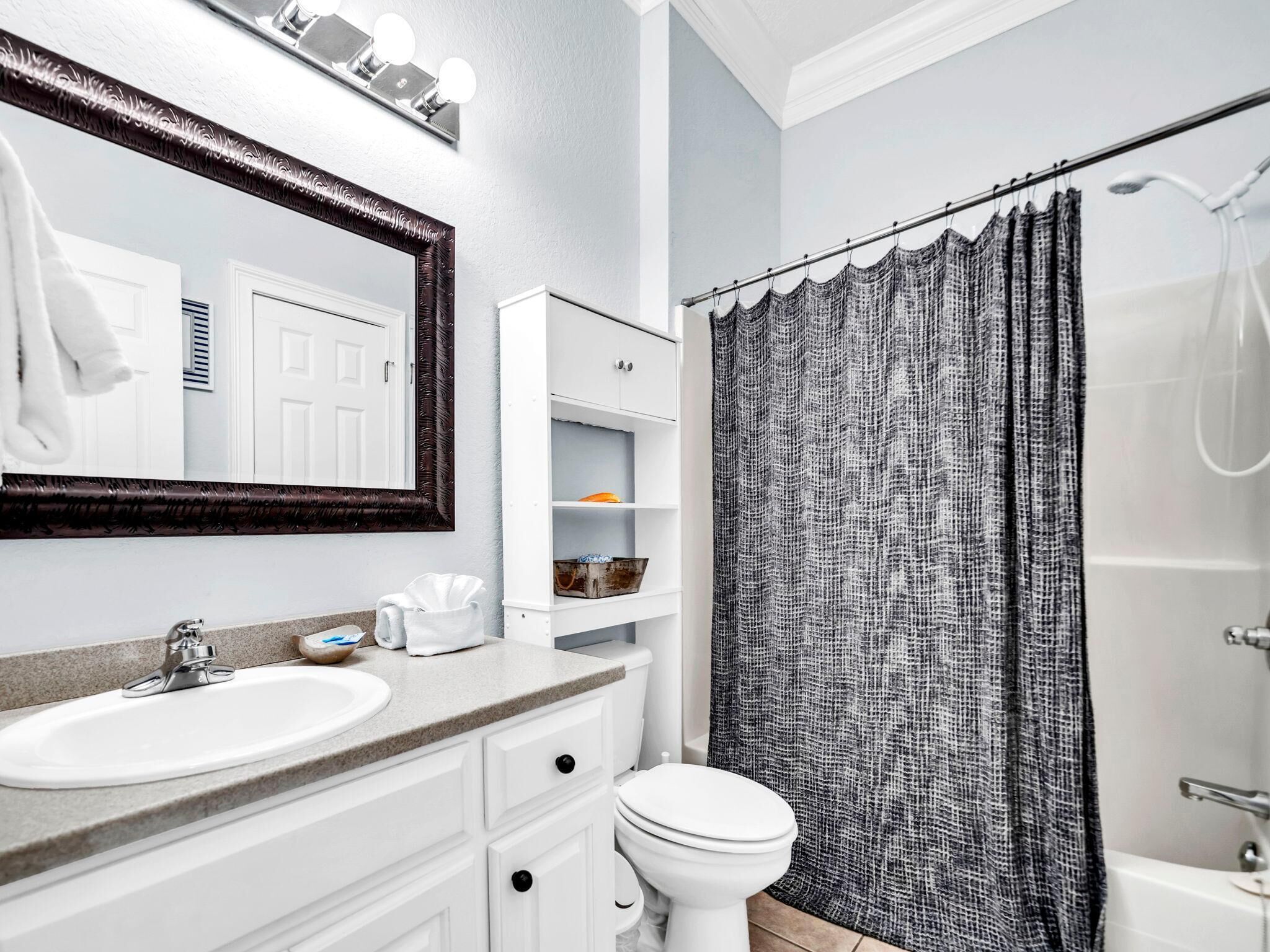 Un baño con lavamanos, inodoro y cortina de ducha.