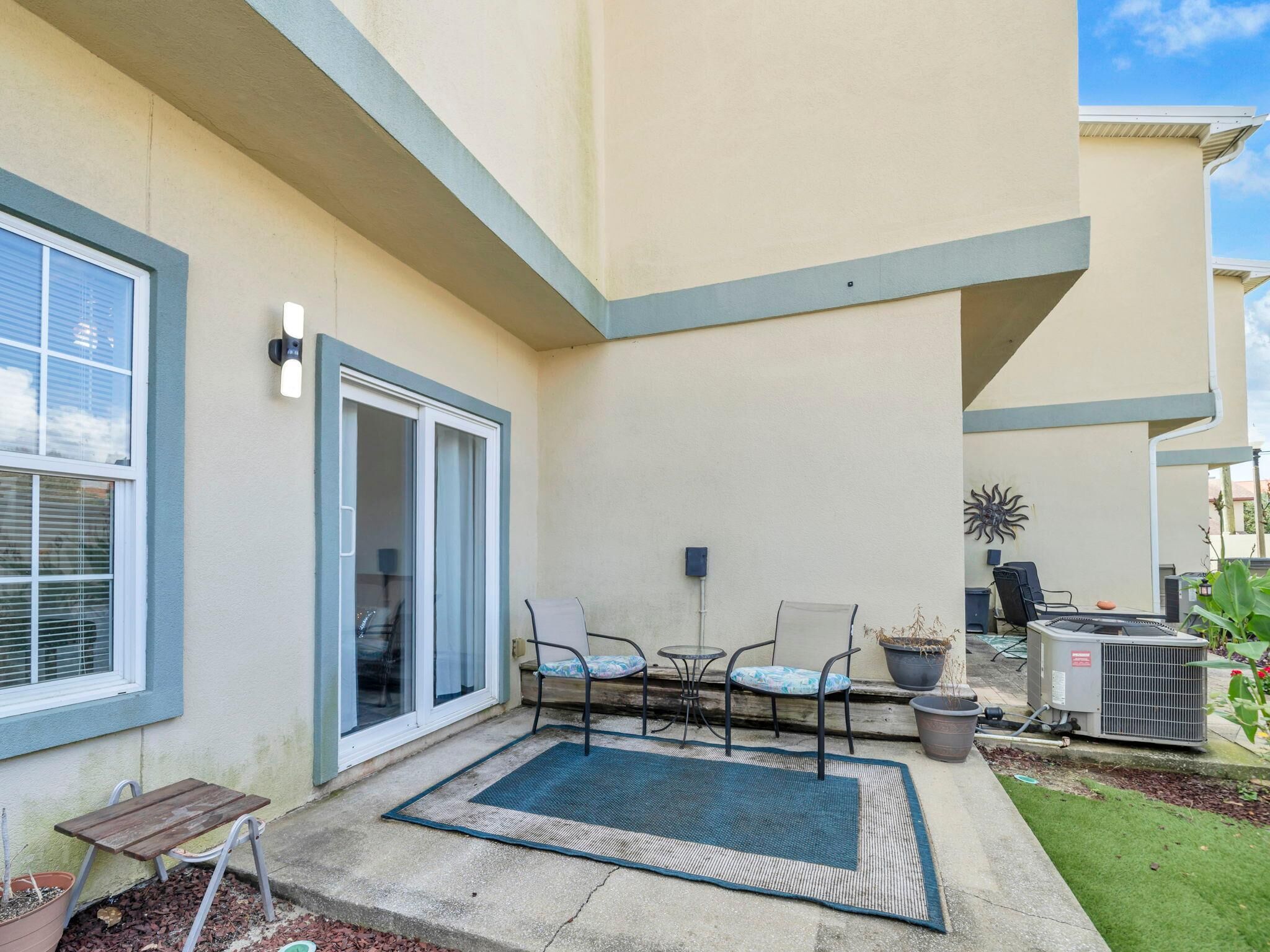 A patio with a table and chairs, a sliding glass door, and an air conditioning unit.