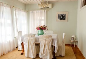 A dining area with a table set for four, white chairs, a vase of flowers, and a framed picture on the wall. - The Dream Villa Kastoria (Kastoria)