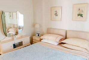 A bedroom with a bed, bedside table, mirror, lamp, and framed floral artwork on the wall. - The Dream Villa Kastoria (Kastoria)