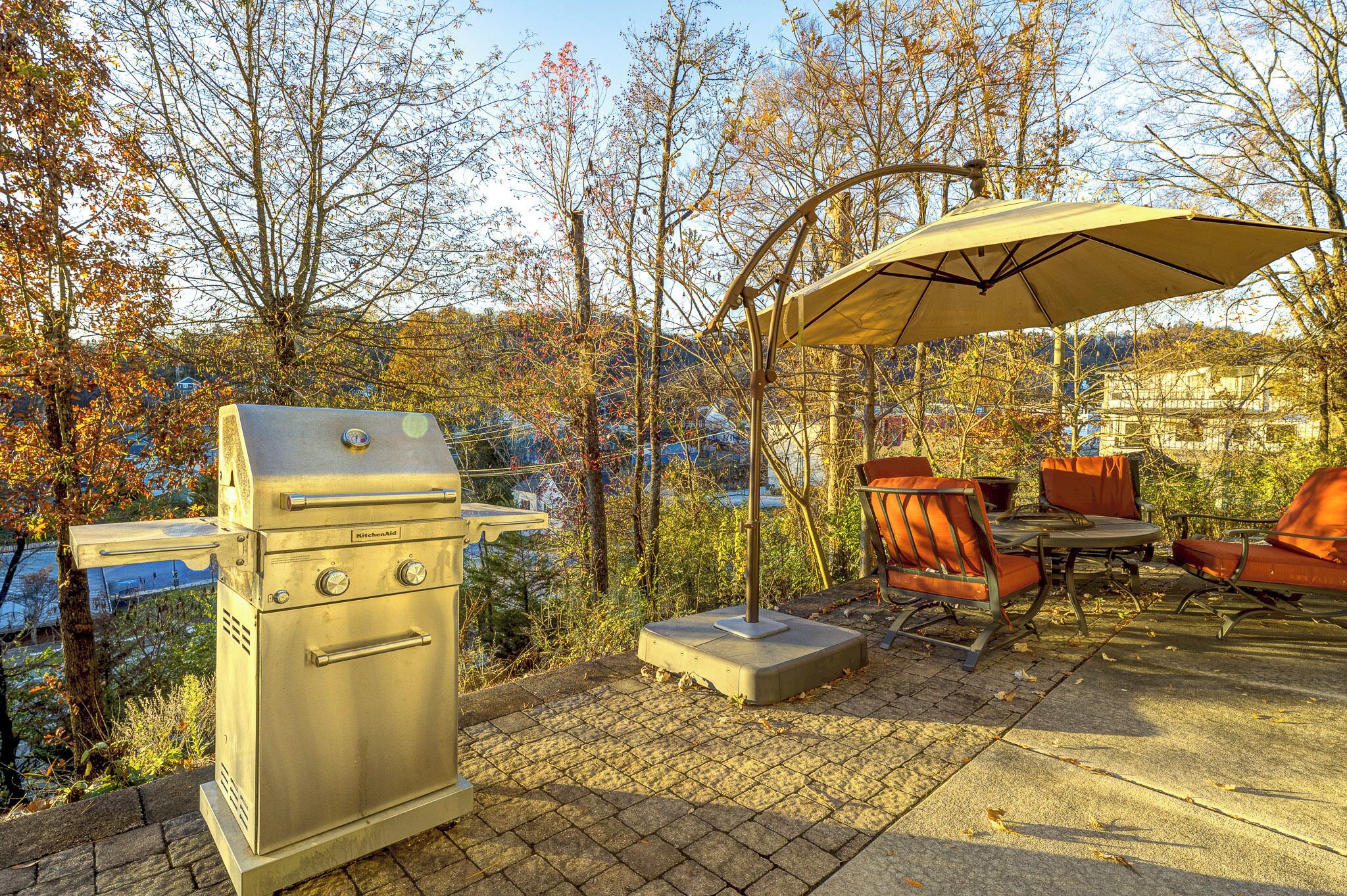 Eine Terrasse im Freien mit Grill, Stühlen und Sonnenschirm.