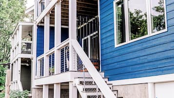 Een meerlaags huis met een blauwe gevel, witte leuningen en een trap die naar de bovenverdieping leidt.