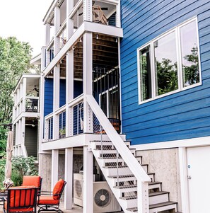 Una casa de varios pisos con fachada azul, barandillas blancas y una escalera que conduce al nivel superior.