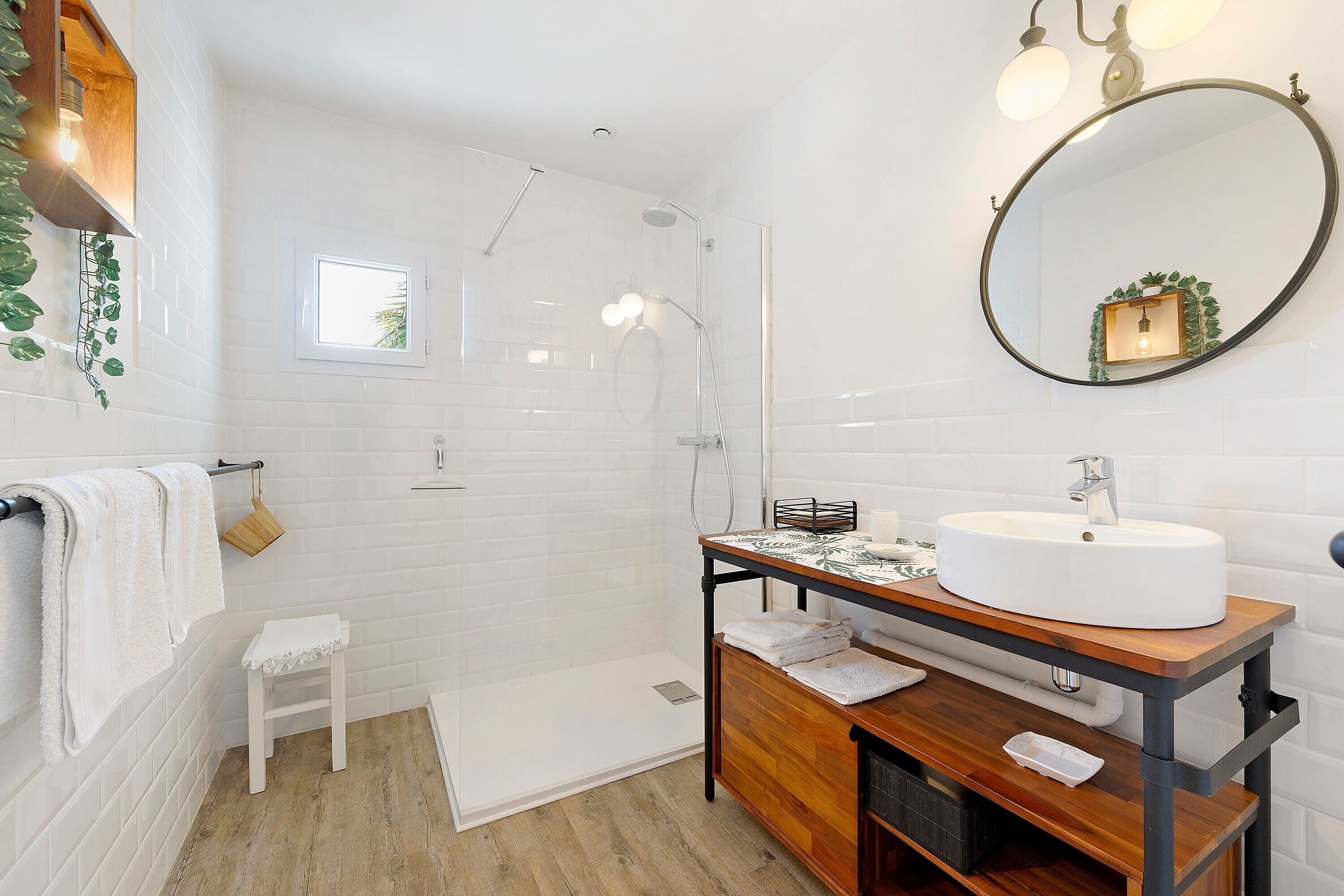 A bathroom with a white sink, wooden vanity, and a large mirror.