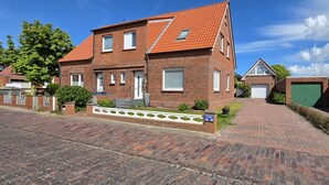 A two-story brick house with a red-tiled roof, a front entrance, and a paved driveway.