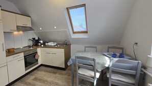 A compact kitchen with a dining area, a small window, and a built-in oven.