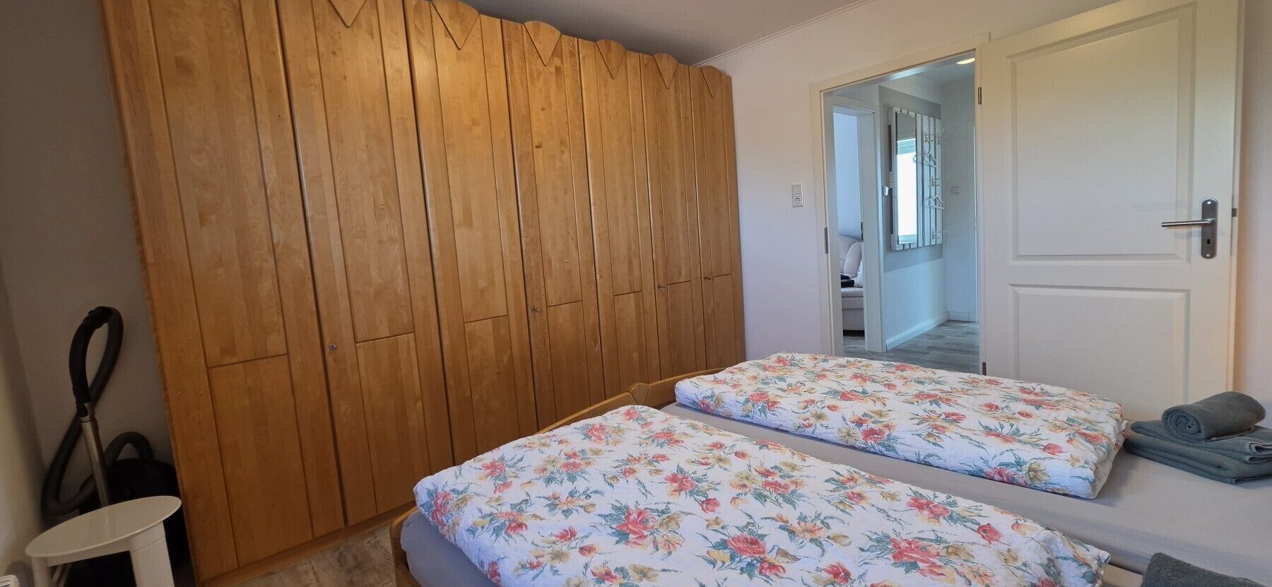 Un dormitorio con dos camas, un armario de madera, una puerta blanca y un espejo.