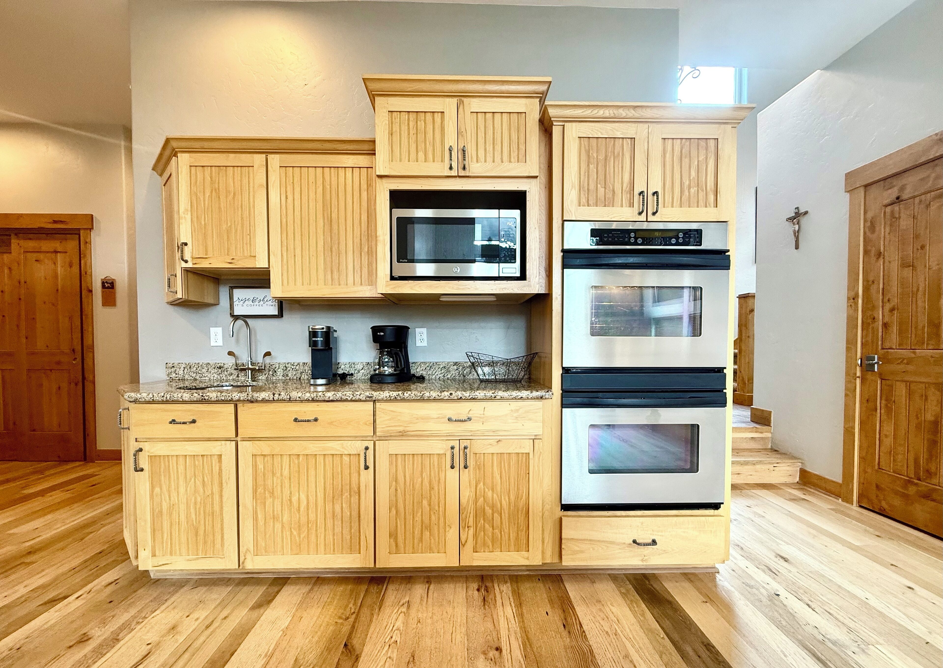 A kitchen with wooden cabinets, a microwave, and two ovens.