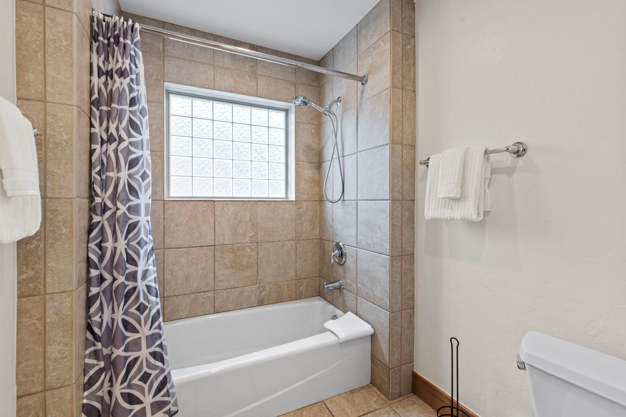 A bathroom with a bathtub, shower, and window.