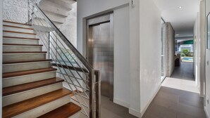 A modern interior with a staircase, elevator, and a view of a pool. - Vacation Villa 'Playa Del Duque' with Private Terrace, Wi-Fi and Air Conditioning (Adeje)
