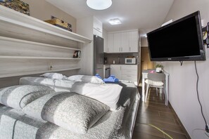 Une chambre avec un lit, une télévision, un coin cuisine et un bureau.
