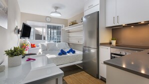 Eine moderne Küche mit integriertem Kühlschrank, Herd und Mikrowelle. Es gibt einen kleinen Essbereich mit Tisch und Stühlen.