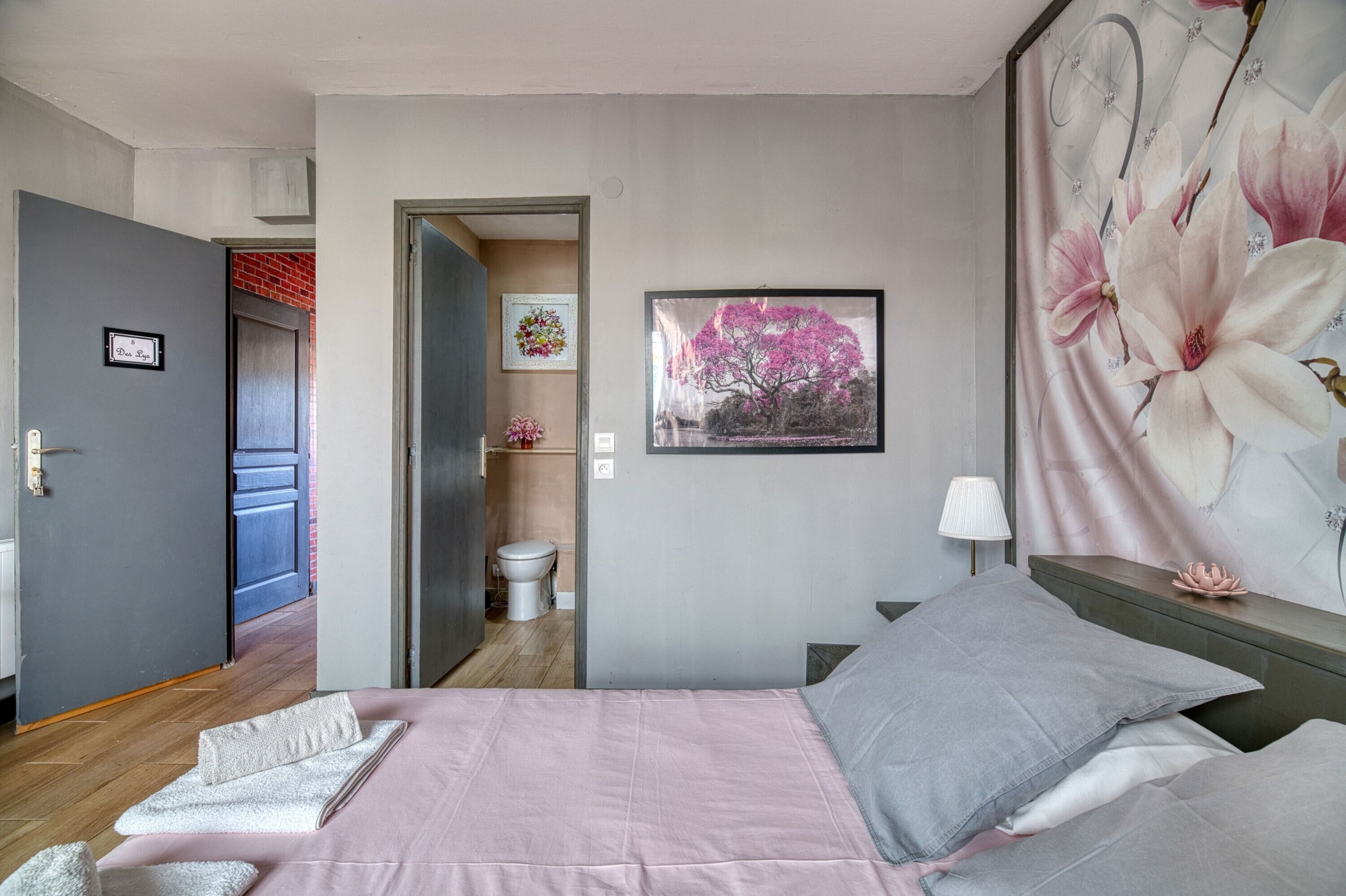 Een slaapkamer met een bed, een nachtkastje, een wandlamp en een deur naar een badkamer.