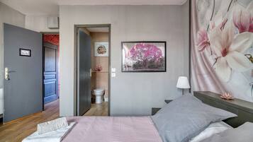 Een slaapkamer met een bed, een nachtkastje, een wandlamp en een deur naar een badkamer.