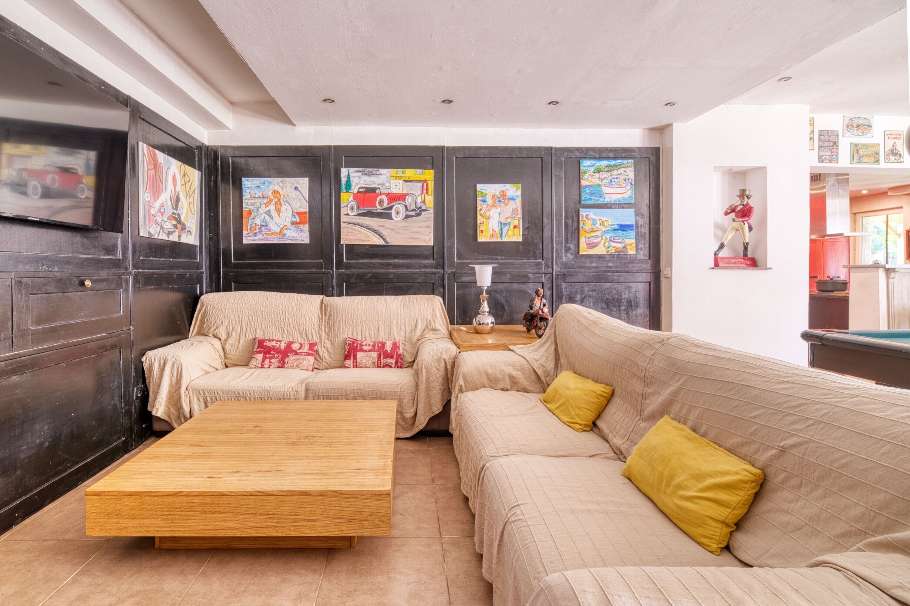 Un salon avec un canapé, une table basse et des œuvres d’art accrochées aux murs.