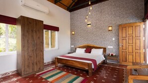 A bedroom with a wooden bed, a wardrobe, a nightstand, and a stone wall. - Johns Village  (Mulanthuruthy)