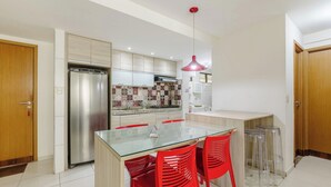 A modern kitchen with a glass dining table, red chairs, and a stainless steel refrigerator. - 2 Bedroom Apartment 700 m From the Beach Mbr0108 (Maceió)