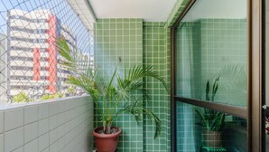 A balcony with green tiled walls, potted plants, and a view of a building with red accents. - 2 Bedroom Apartment 700 m From the Beach Mbr0108 (Maceió)