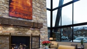 A lobby with a stone fireplace, leather sofas, and a large window offering a view of the outside.