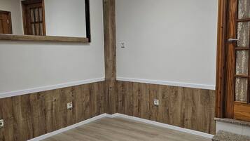 Una habitación con un espejo grande, paneles de madera y una puerta de madera con un panel de vidrio.