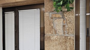 A room with two dark wooden doors, a stone pillar with a plant, and a window with blinds. - Real 43 Casa Neda (neda)