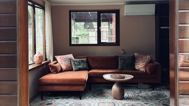 A cozy living room with a brown sectional sofa, a round coffee table, and a patterned rug. - Chaletpark Kempenbos - 196 (Diessen)