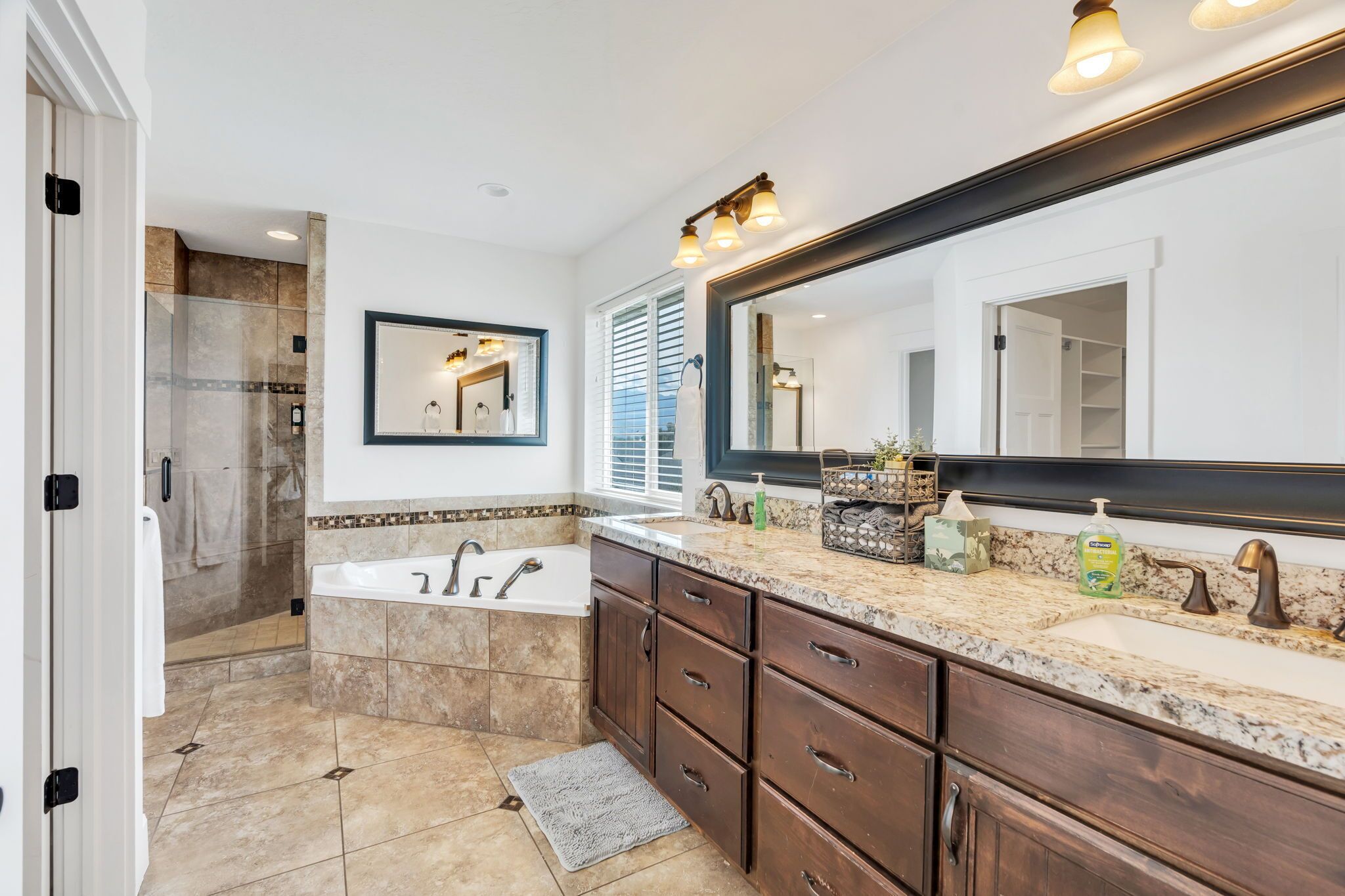 A bathroom with a large mirror, a bathtub, and a shower area.