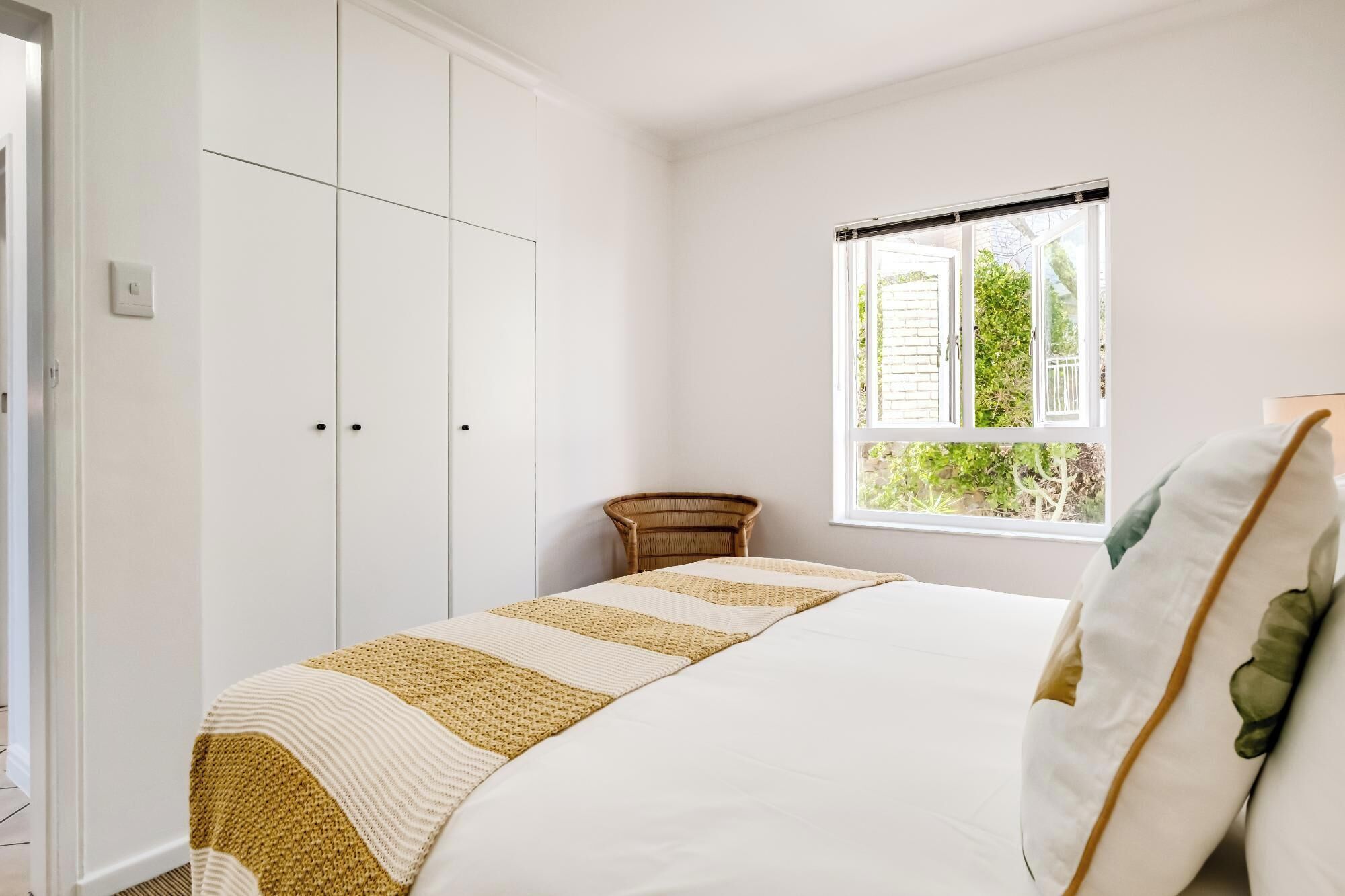 A bedroom with a bed, a window, a chair, and a wardrobe.