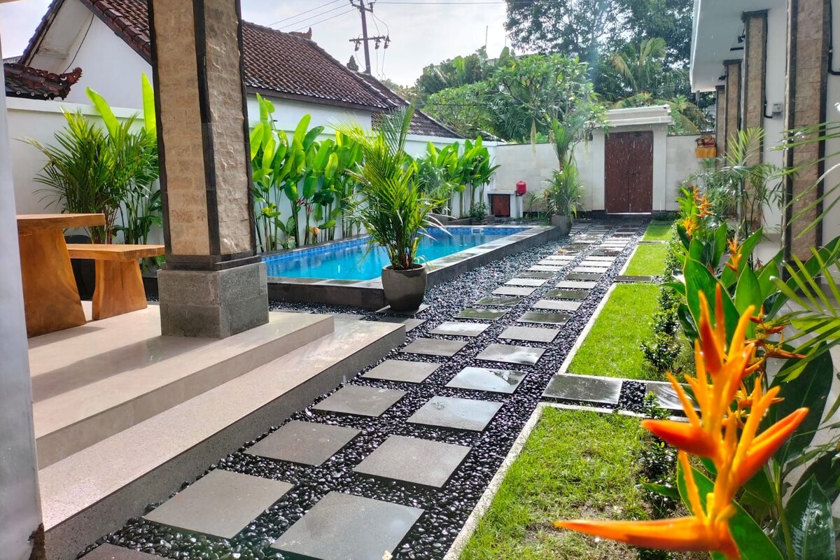 A pool area with a stone pathway, potted plants, and a bench.