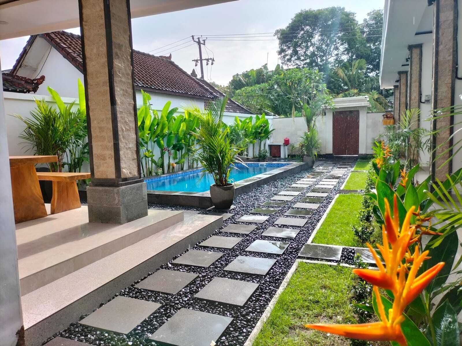 A pool area with a stone pathway, potted plants, and a bench.