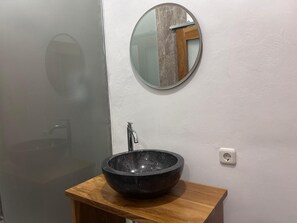 A bathroom with a round mirror, a black vessel sink, and a wooden countertop. - Alit Guest House (Jimbaran)