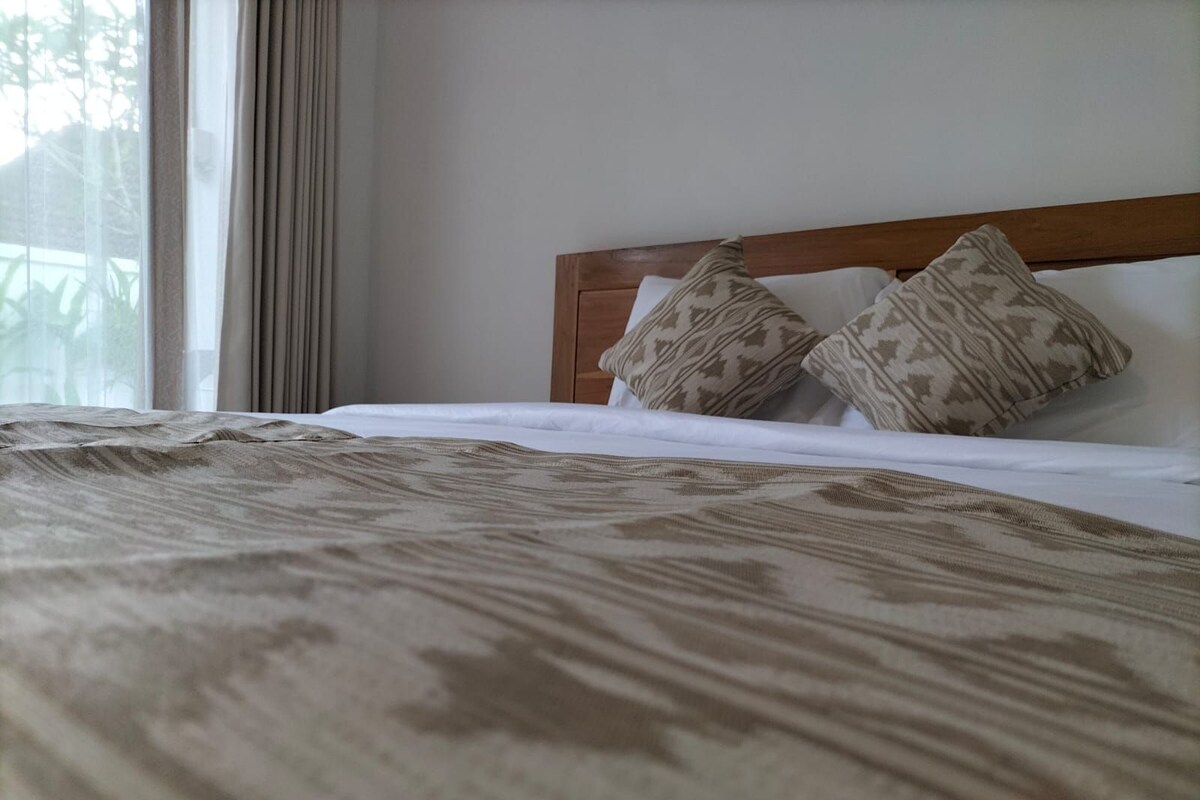 A bed with a patterned bedspread, a wooden headboard, and two patterned pillows.