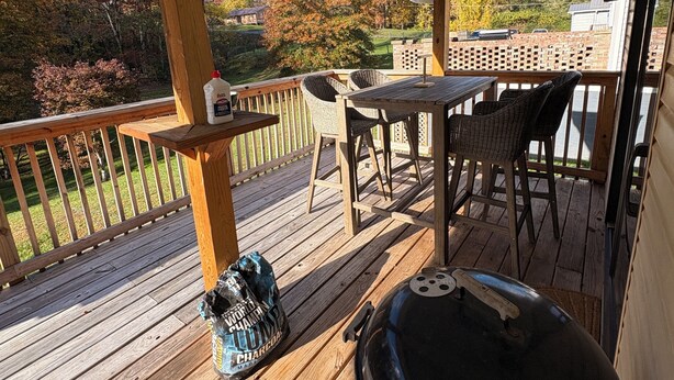 Eine überdachte Terrasse im Freien mit Grill, Sitzgelegenheit und Blick auf eine Wohngegend.
